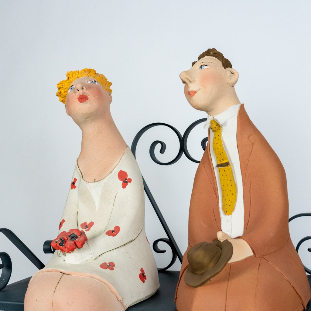 Zoom sur le couple amoureux 18 d’Evelyne Almayrac, sculpture unique en grès réfractaire représentant un couple assis côte à côte sur un banc en fer forgé.