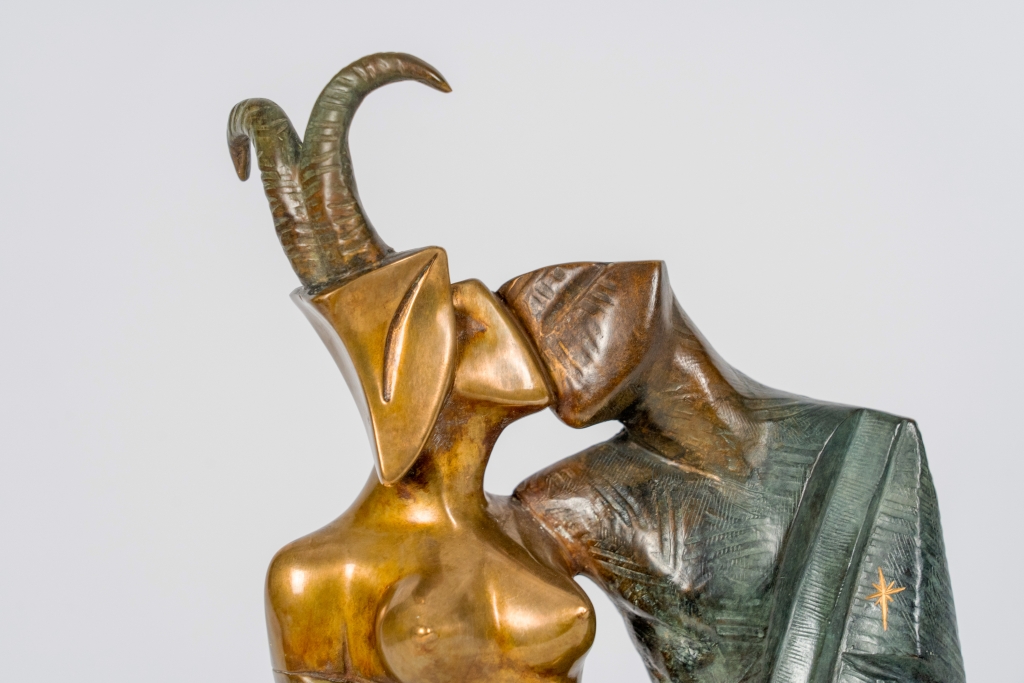 Zoom de Capricorne d’Arsen Avetissian, sculpture contemporaine en bronze représentant un couple enlacé. La figure féminine, coiffée de cornes de capricorne, enlace une silhouette masculine stylisée dans une composition élégante aux patines dorées, brunes et vertes.