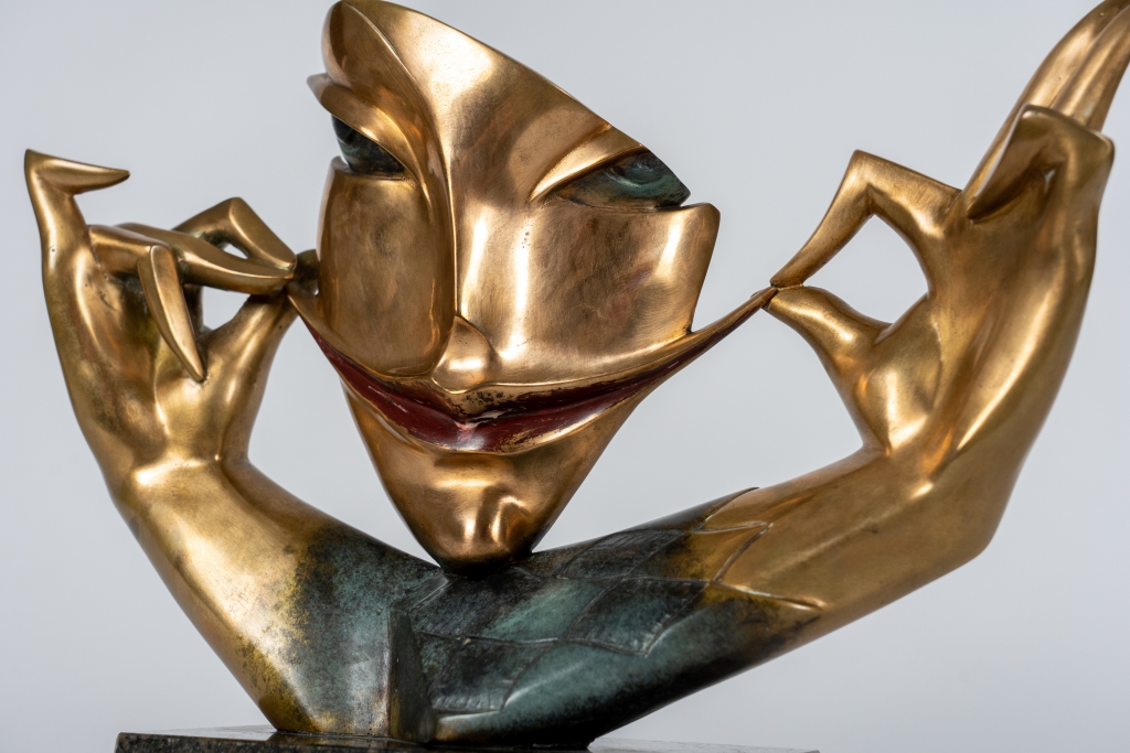 Vue de Jeu de sourire d'Arsen Avetissian, sculpture contemporaine en bronze représentant un visage stylisé aux lèvres esquissant un large sourire, encadré par deux mains élégamment levées qui semblent en souligner l'expression. L'œuvre repose sur un socle en pierre et joue sur l'équilibre entre humour, élégance et raffinement.