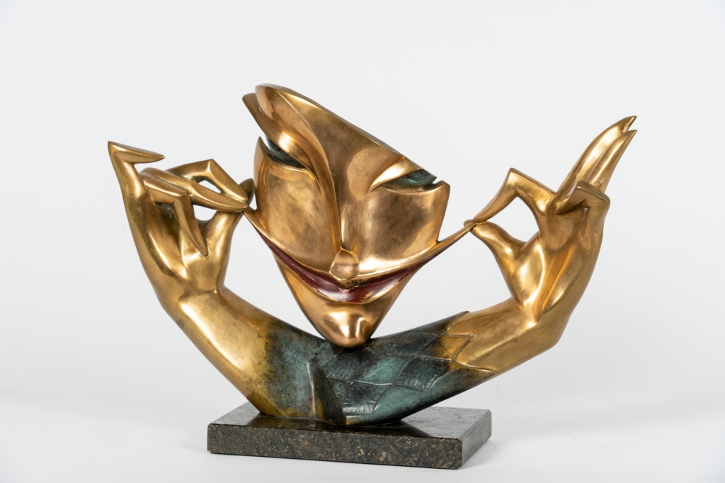 Jeu de sourire d'Arsen Avetissian, sculpture contemporaine en bronze représentant un visage stylisé aux lèvres esquissant un large sourire, encadré par deux mains élégamment levées qui semblent en souligner l'expression. L'œuvre repose sur un socle en pierre et joue sur l'équilibre entre humour, élégance et raffinement.