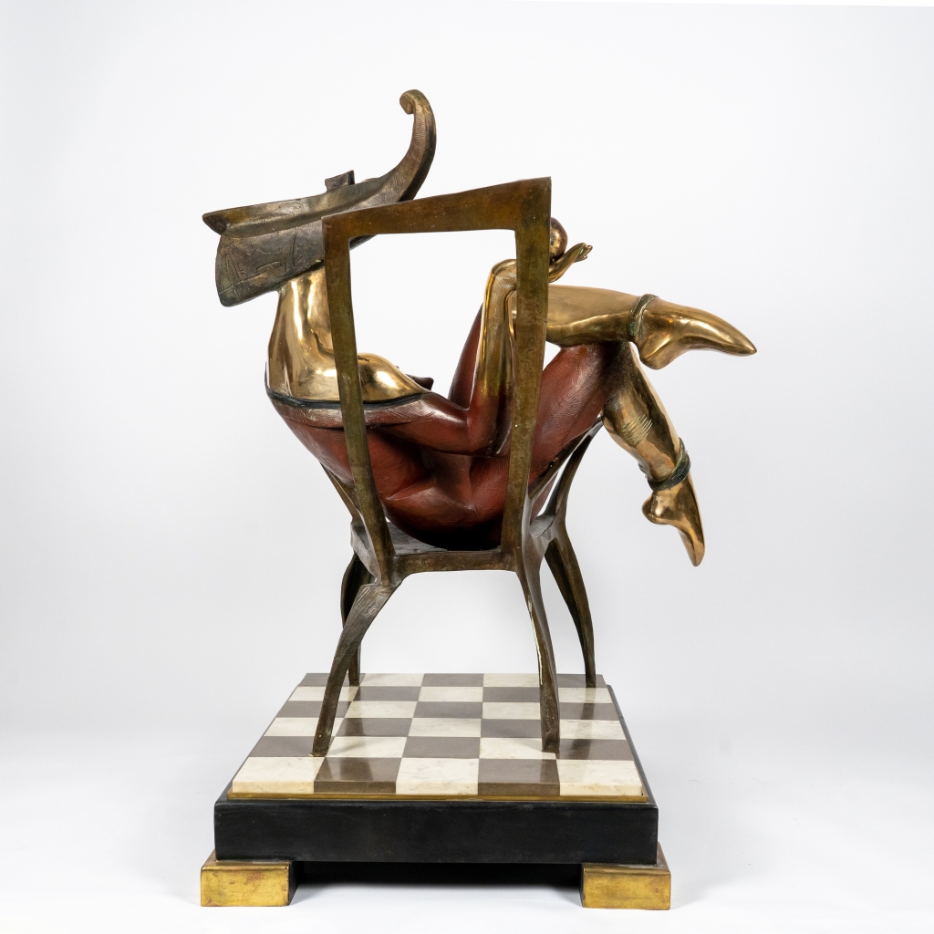 Dos de La Reine de trèfle d’Arsen Avetissian, sculpture en bronze représentant une figure féminine stylisée assise sur un fauteuil, jambes croisées, évoluant dans un univers inspiré du jeu de cartes. L’œuvre repose sur un damier noir et blanc qui renforce son caractère symbolique et théâtral.