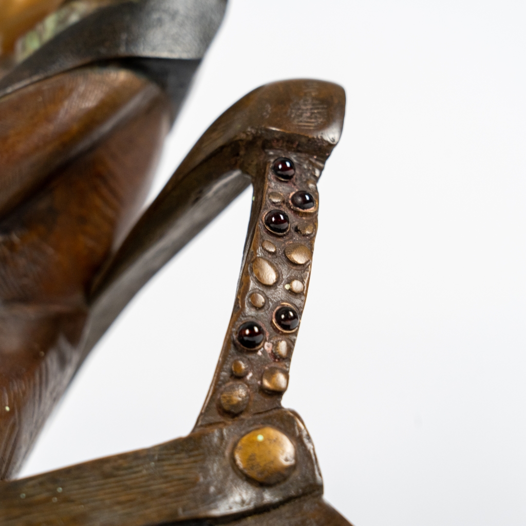 Detail du trone de La Reine de trèfle d’Arsen Avetissian, sculpture en bronze représentant une figure féminine stylisée assise sur un fauteuil, jambes croisées, évoluant dans un univers inspiré du jeu de cartes. L’œuvre repose sur un damier noir et blanc qui renforce son caractère symbolique et théâtral.