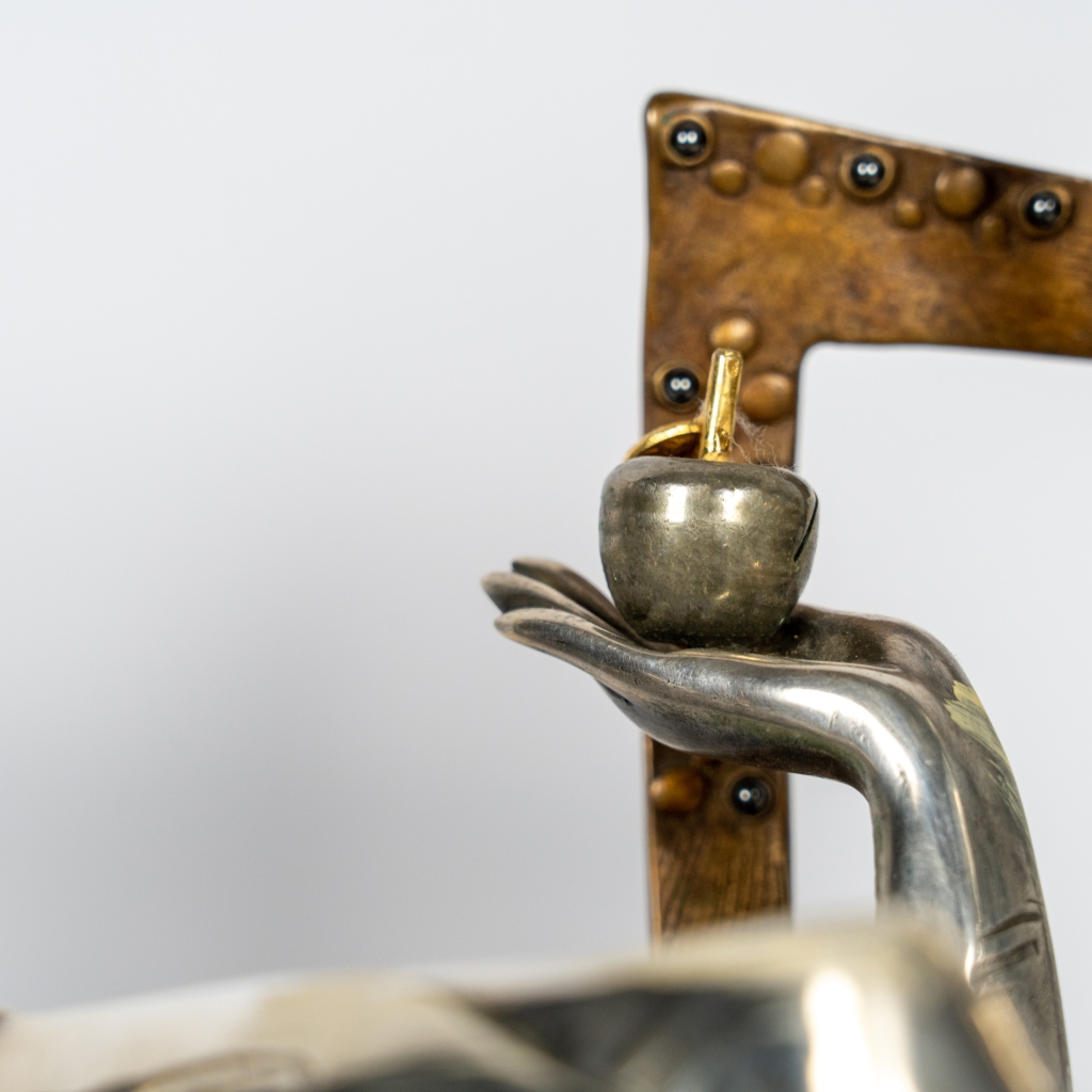 Detail de la main de la Reine de trèfle d’Arsen Avetissian, sculpture en bronze et argenture représentant une élégante figure féminine assise dans un fauteuil stylisé, tenant une pomme. L’œuvre mêle raffinement, symbolisme et influences du jeu de cartes dans une composition contemporaine aux lignes sculpturales affirmées.