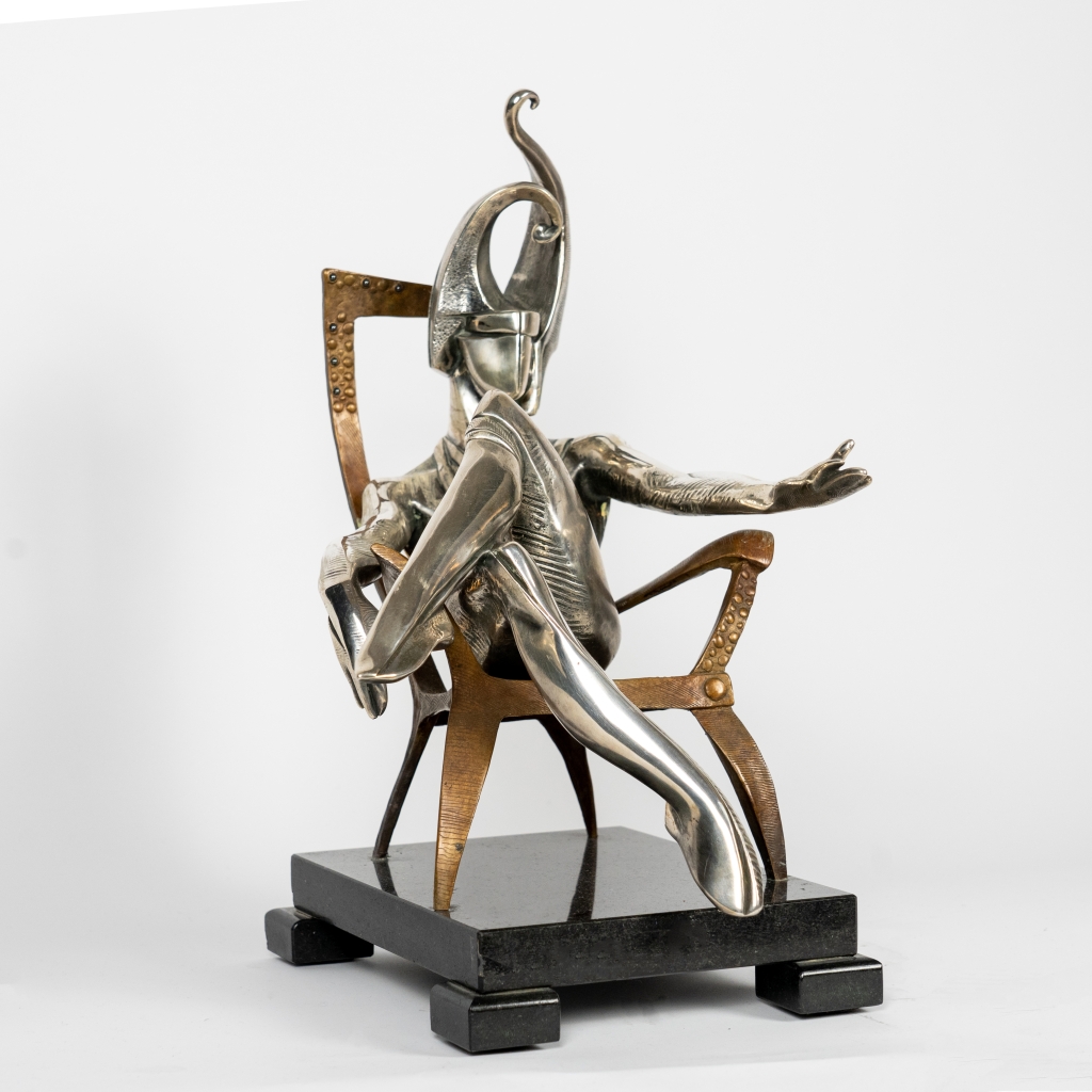 Vue de trois quarts du Roi de Trèfle d'Arsen Avetissian, sculpture contemporaine en bronze et argenture représentant un personnage royal stylisé assis avec élégance sur un fauteuil. Son casque monumental aux courbes évoquant le trèfle et ses surfaces argentées confèrent à l'œuvre une présence majestueuse et théâtrale.