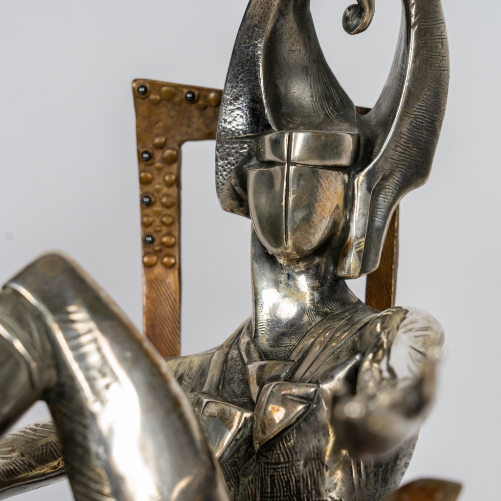 Detail du visage du Roi de Trèfle d'Arsen Avetissian, sculpture contemporaine en bronze et argenture représentant un personnage royal stylisé assis avec élégance sur un fauteuil. Son casque monumental aux courbes évoquant le trèfle et ses surfaces argentées confèrent à l'œuvre une présence majestueuse et théâtrale.