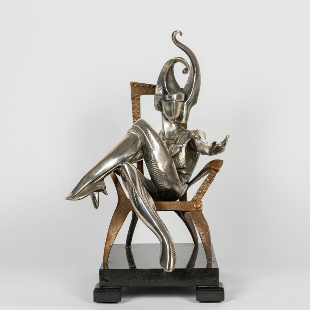 Roi de Trèfle d'Arsen Avetissian, sculpture contemporaine en bronze et argenture représentant un personnage royal stylisé assis avec élégance sur un fauteuil. Son casque monumental aux courbes évoquant le trèfle et ses surfaces argentées confèrent à l'œuvre une présence majestueuse et théâtrale.