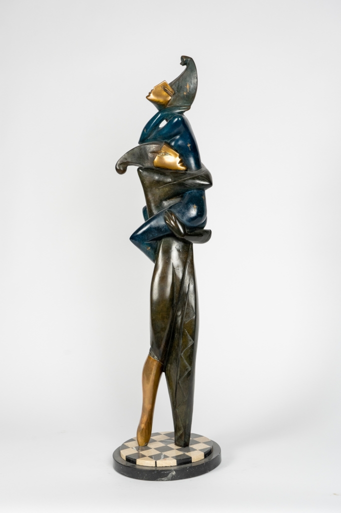 Star à Venise d'Arsen Avetissian, sculpture contemporaine en bronze représentant un personnage élancé portant dans ses bras une figure masquée. Les silhouettes stylisées, aux patines bleues, dorées et vertes, reposent sur un socle circulaire en damier évoquant l'univers du carnaval vénitien.