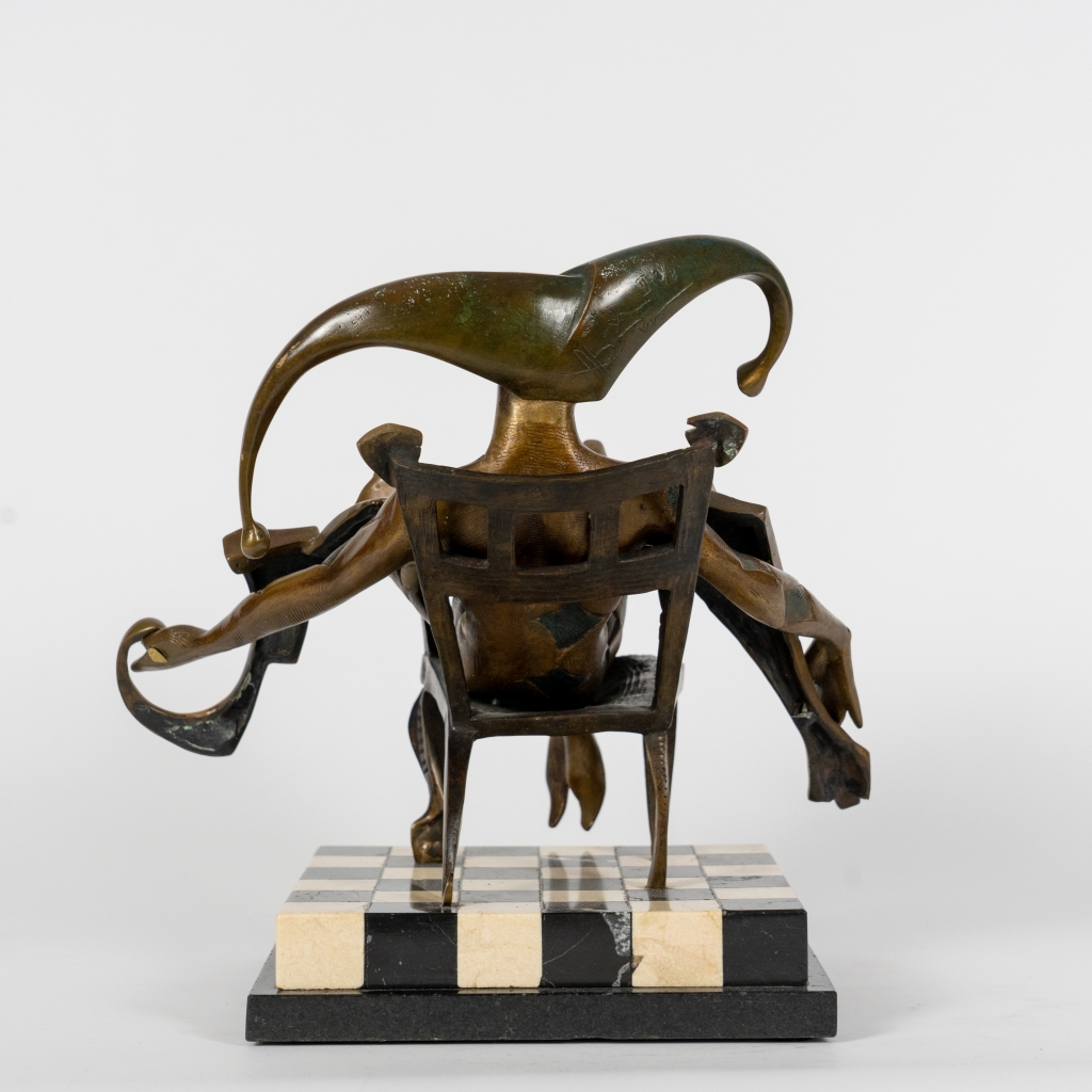 Vue de dos de Le Seigneur d'Arsen Avetissian, sculpture contemporaine en bronze représentant un personnage majestueux installé dans un fauteuil. Les jambes croisées, les bras largement ouverts et l'imposante coiffe en croissant composent une silhouette théâtrale évoquant l'autorité, la sérénité et l'élégance.