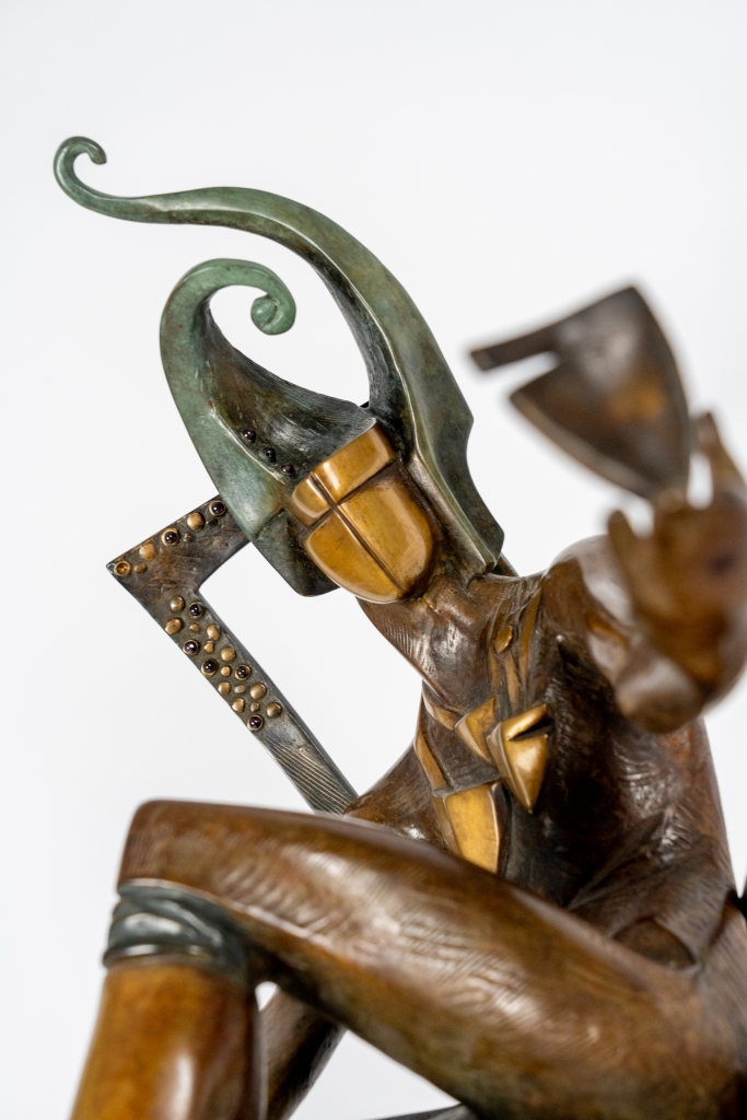 Zoom sur The King of Club d'Arsen Avetissian, sculpture contemporaine en bronze représentant un souverain stylisé assis sur un fauteuil, tenant une coupe dans un geste d'invitation. Son imposant couvre-chef aux courbes élancées évoque le trèfle et souligne l'élégance théâtrale de la composition.