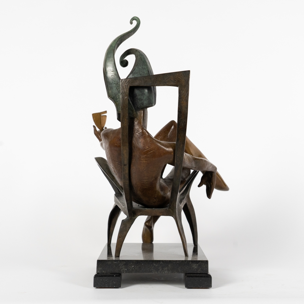 Le dos de The King of Club d'Arsen Avetissian, sculpture contemporaine en bronze représentant un souverain stylisé assis sur un fauteuil, tenant une coupe dans un geste d'invitation. Son imposant couvre-chef aux courbes élancées évoque le trèfle et souligne l'élégance théâtrale de la composition.
