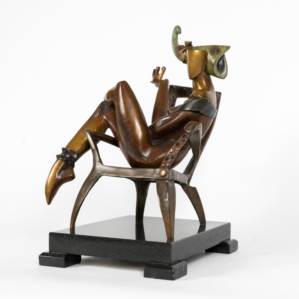 Vue de trois quarts de The Queen of Club d'Arsen Avetissian, sculpture contemporaine en bronze représentant une reine élégamment installée dans un fauteuil. Les jambes repliées, les bras croisés et la coiffe monumentale évoquent une souveraine à la fois mystérieuse, indépendante et pleine d'assurance.