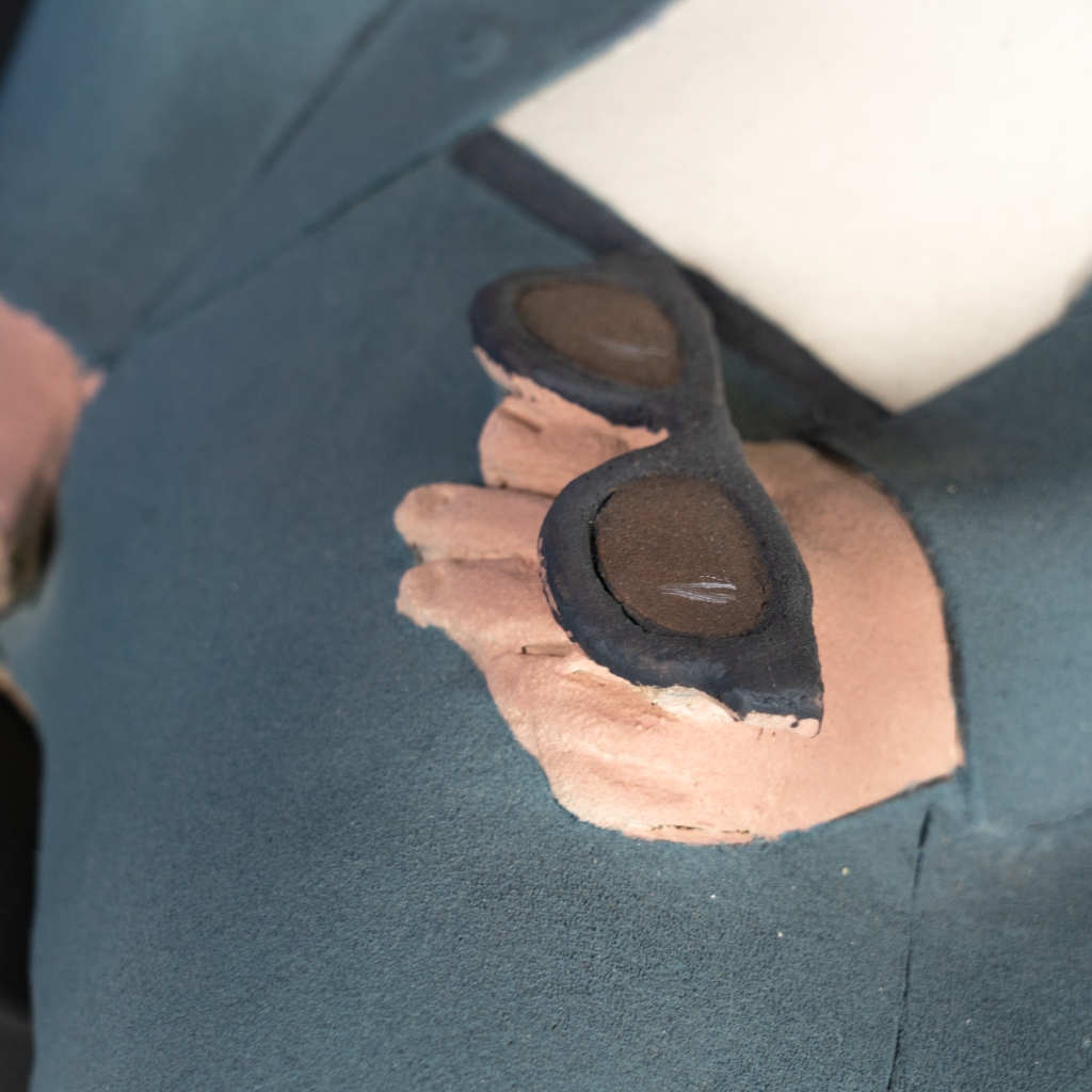 Detail des lunettes du couple amoureux 10 d’Evelyne Almayrac, sculpture unique en grès réfractaire représentant un couple assis sur un banc en fer forgé dans une scène pleine de tendresse.