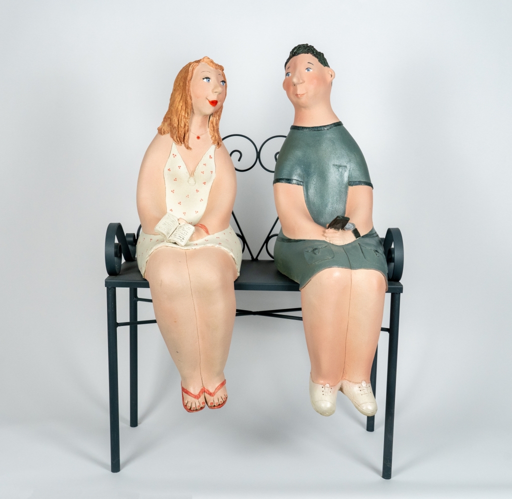 Couple amoureux 4 d’Evelyne Almayrac, sculpture unique en grès réfractaire représentant un couple assis sur un banc en fer forgé dans un moment de complicité.