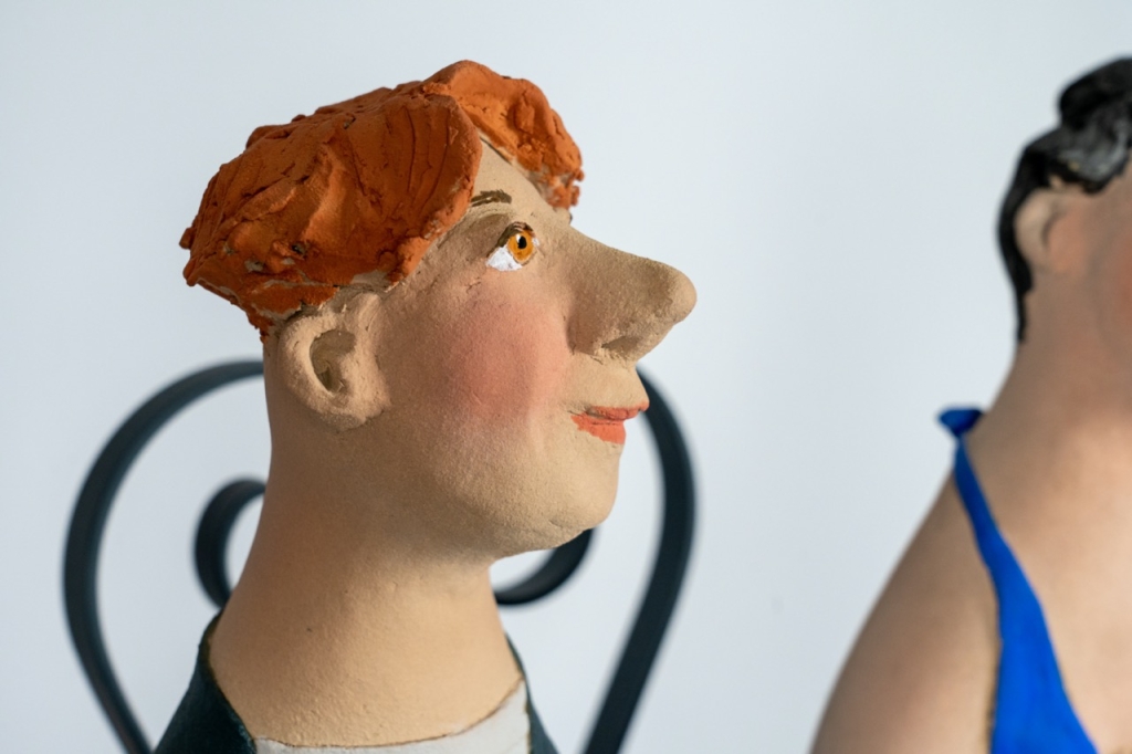 Gros plan sur le couple amoureux 17 d’Evelyne Almayrac, sculpture unique en grès réfractaire représentant un homme et une femme assis sur un banc en fer forgé.