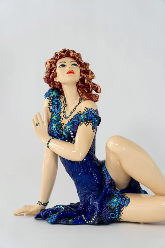 Sculpture en résine Lys de Josepha, figure féminine allongée en robe bleue ornée de motifs délicats, expression de grâce et de féminité.