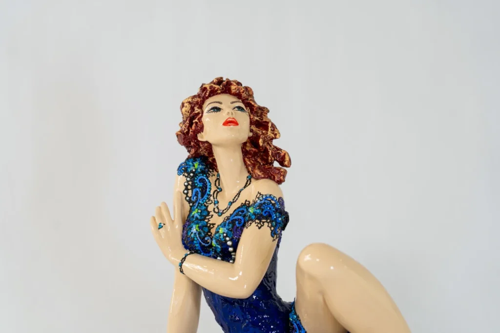 Detail de la sculpture en résine Lys de Josepha, figure féminine allongée en robe bleue ornée de motifs délicats, expression de grâce et de féminité.