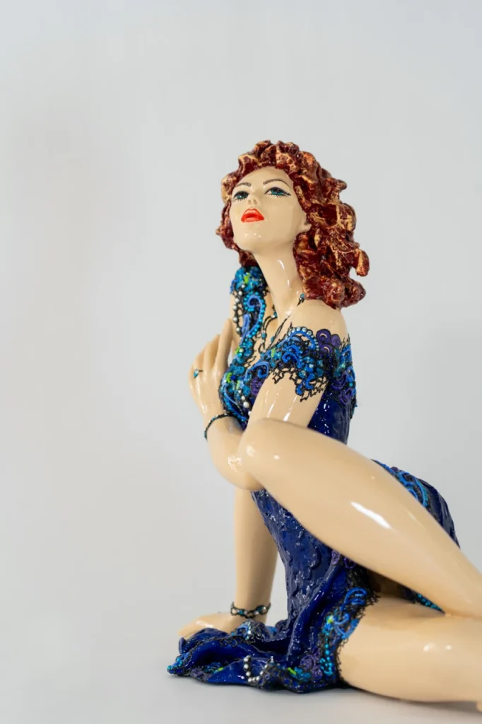 Vue de profil de la sculpture en résine Lys de Josepha, figure féminine allongée en robe bleue ornée de motifs délicats, expression de grâce et de féminité.