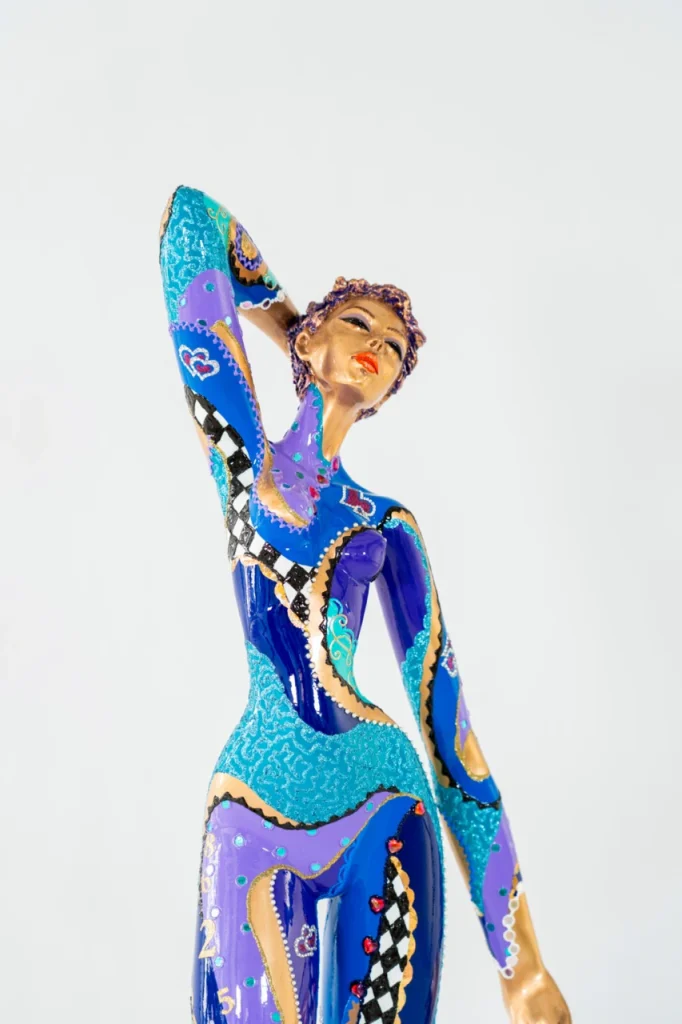 Vue de trois quarts de la sculpture en bronze peint La Perle de Josepha, figure féminine élancée aux nuances de bleu et violet dans une posture élégante et raffinée.