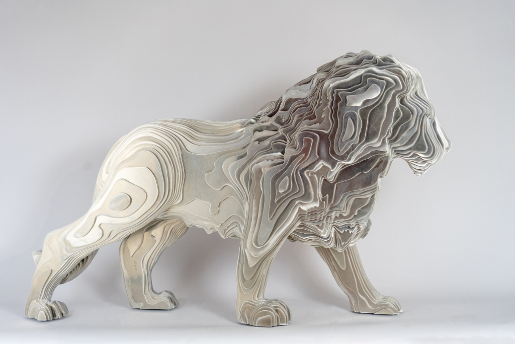 Vue de profil de la sculpture en aluminium brut intitulée REX de Jean Paul KALA, composition figurative représentant le lion sous des lignes épurées et puissantes